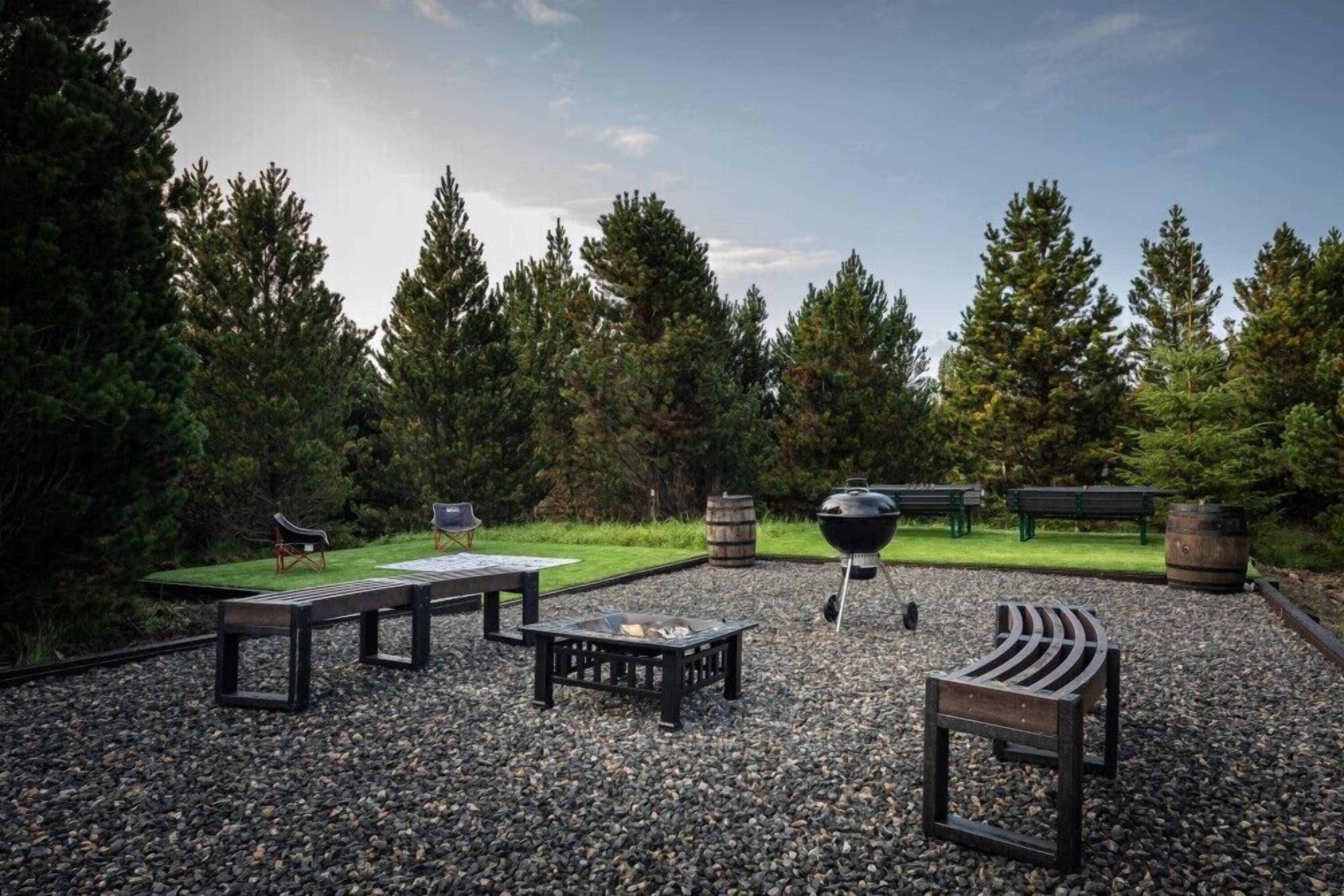 An outdoor seating area with benches, a fire pit, and a grill.