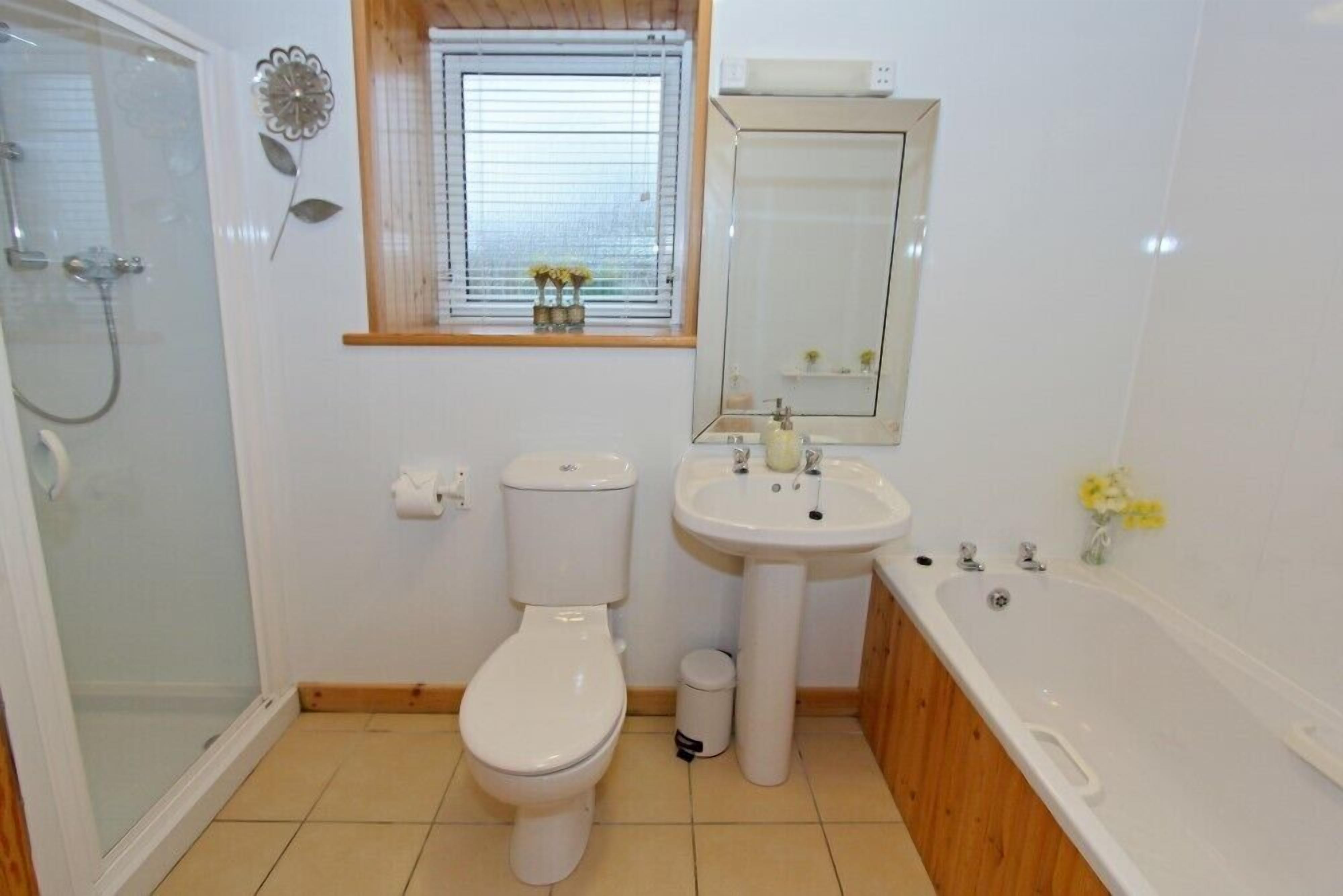 Et badeværelse med toilet, vask og badekar.