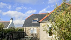 A house with a stone facade, a red roof, and a small window. - Canach Cottage (South Uist)