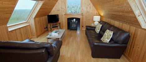 Un interior acogedor de madera con chimenea, sofás de cuero y televisor.