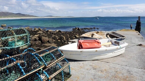 A small boat docked at a pier with fishing traps nearby. - Tulloch House (South Uist)