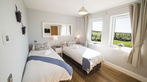 Una camera da letto con due letti, un'ampia finestra vista sulla campagna e una lampada a soffitto.
