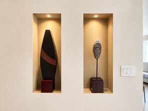 Dos esculturas fijadas a la pared en huecos con iluminación, con un interruptor de luz cerca.
