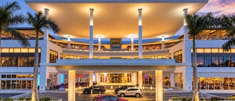 A modern hotel with a multi-level structure, a covered entrance, and a parking area with cars.
