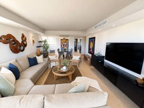 Una sala de estar moderna con un conjunto de sofás, una mesa de centro, un televisor de pantalla plana y obras de arte en las paredes.