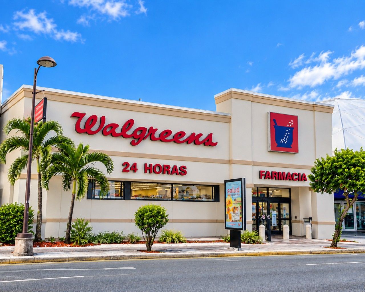A Walgreens store with a 24-hour pharmacy sign, palm trees, and a clear blue sky.