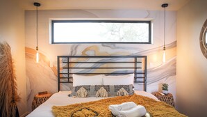Een moderne slaapkamer met een groot bed, een raam en een unieke wanddecoratie.