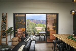 Una sala de estar moderna con un sofá, una mesa de comedor y vistas a las montañas a través de amplios ventanales.