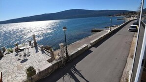 Une promenade en bord de mer, avec un revêtement de sol en pierre, des espaces aménagés pour s’asseoir et un vélo garé sur le côté.
