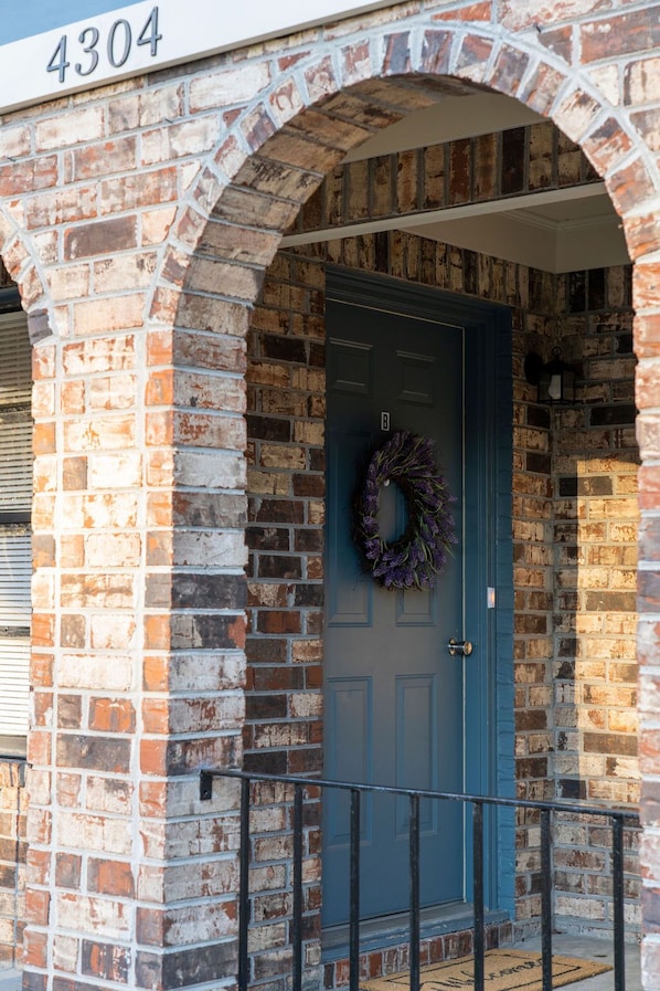 Stunning entrance to a charming brick building with a decorative wreath and a welcoming doormat.