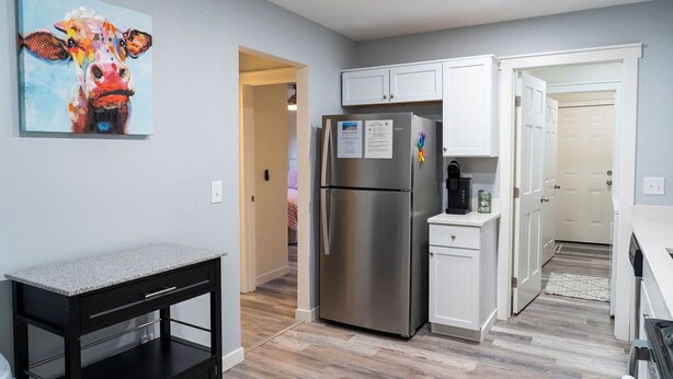 A modern kitchen with a stainless steel refrigerator, white cabinets, and a granite countertop. - Madrona's Cottage B- Your Central Hub to Charleston! 5 Min From Airport (North Charleston)