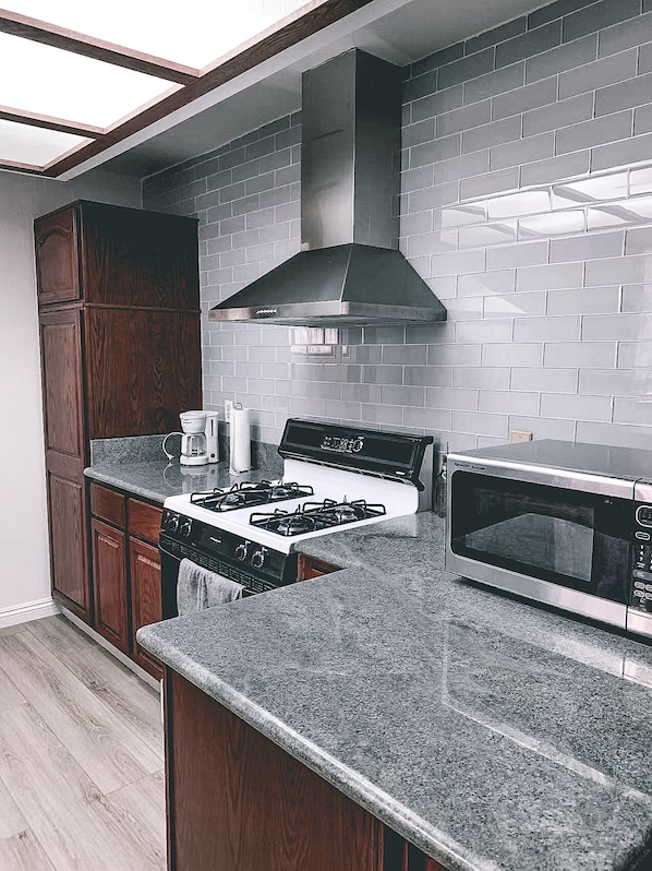 Enjoy cooking in this well-equipped kitchen with a stainless steel range hood, microwave, and gas stove.
