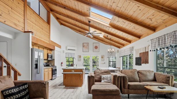 Un ampio soggiorno con soffitto alto, travi in legno, una cucina dotata di elettrodomestici moderni e un'area pranzo con vista.