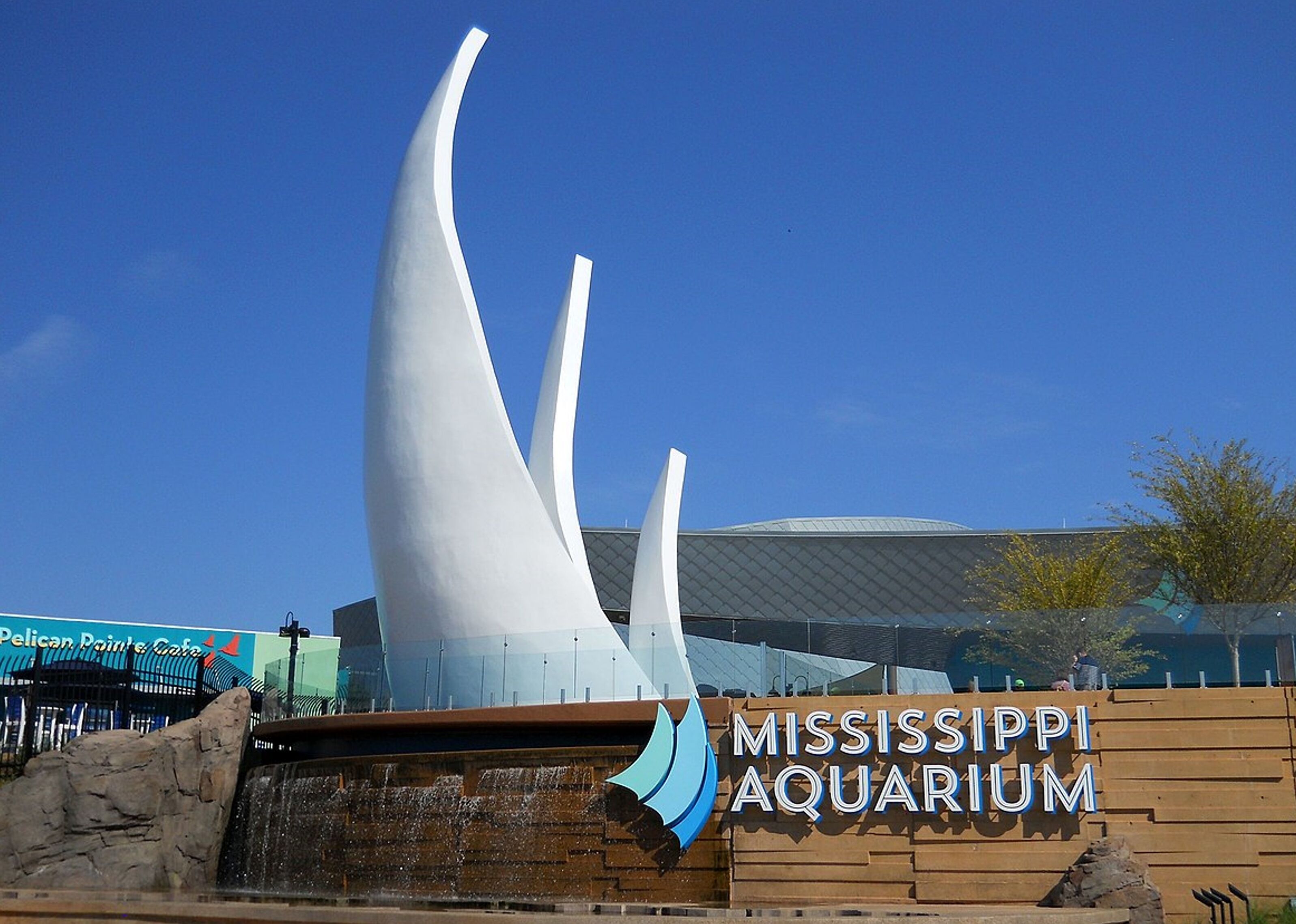 The exterior of the Mississippi Aquarium with a distinctive white sculpture and a clear blue sky.