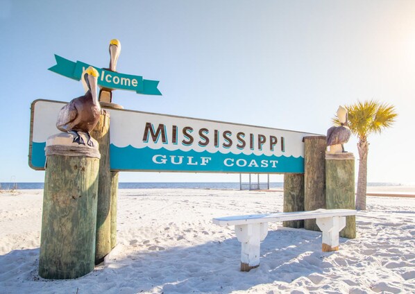Un cartel de playa con la inscripción 'Mississippi Gulf Coast' y una escultura de pelícano.