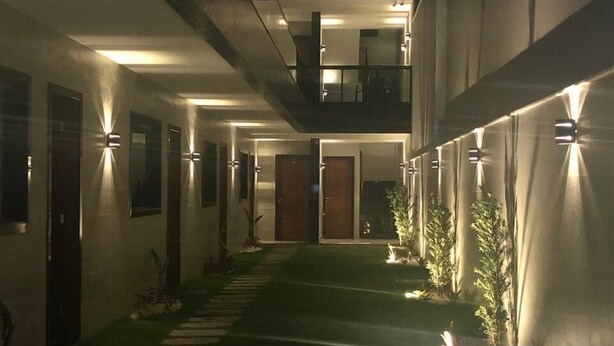 Un edificio moderno con una zona esterna coperta, caratterizzata da un percorso centrale e diverse porte.