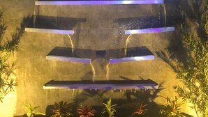 Una fontana a livelli con gradini illuminati e piante alla base.