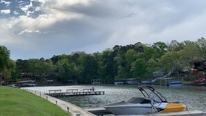 A lakeside dock with a boat, picnic tables, and a grassy area. - Adorable Lake Getaway (Hot Springs)