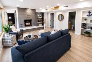 A modern living room with a fireplace, a sofa, a coffee table, and a bookshelf.