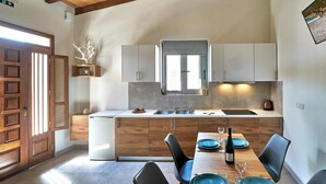 Eine moderne Küche mit Holzschränken, einem eingebauten Backofen und einem Essbereich mit gedecktem Tisch für zwei Personen.