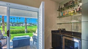 A modern kitchen with a wine rack, a glass door leading to a patio with a view of a golf course. - Beautiful Desert Falls home right on the golf course (Palm Desert)