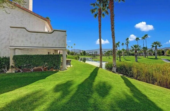 A well-maintained lawn with a pathway leading to a building with a white facade and a curved design element.