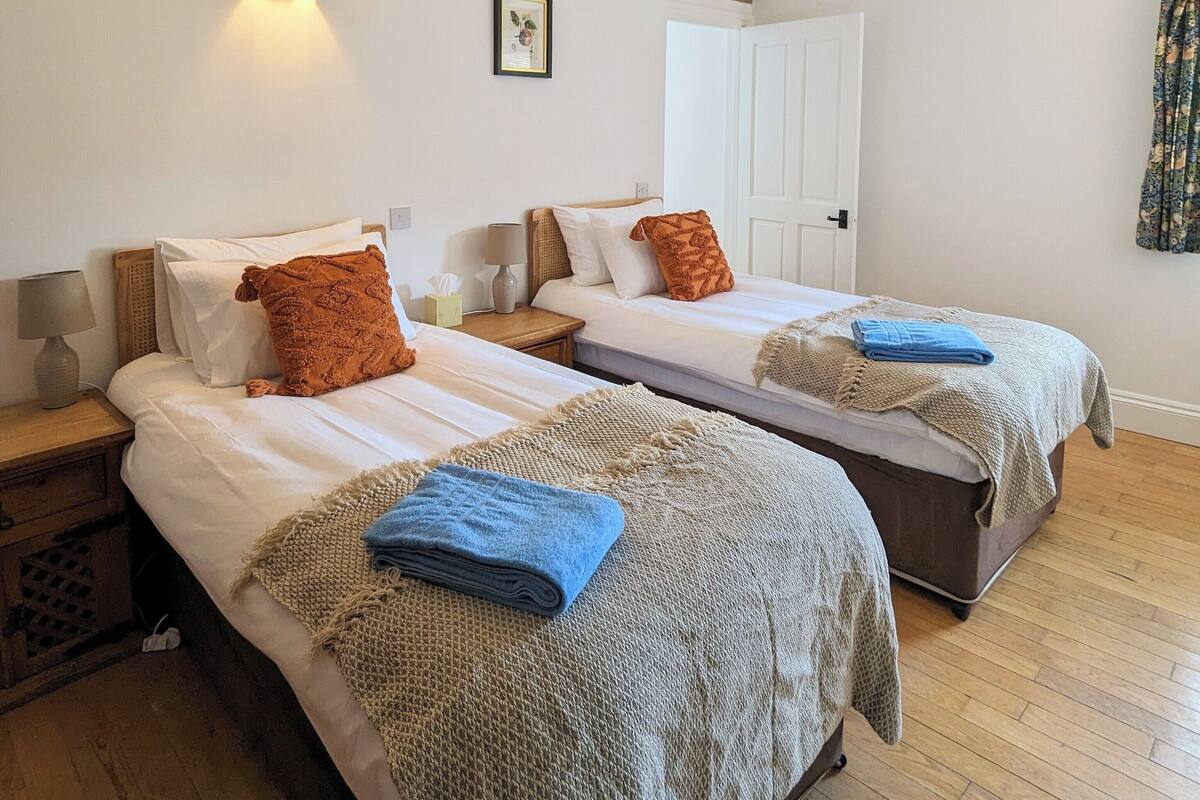 A hotel room with two beds, a wall-mounted light, a framed picture, and a wooden floor.