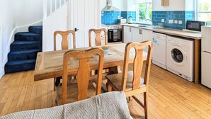 Una cocina rústica con vigas de madera a la vista, un comedor con sillas de madera y un salpicadero con azulejos azules.