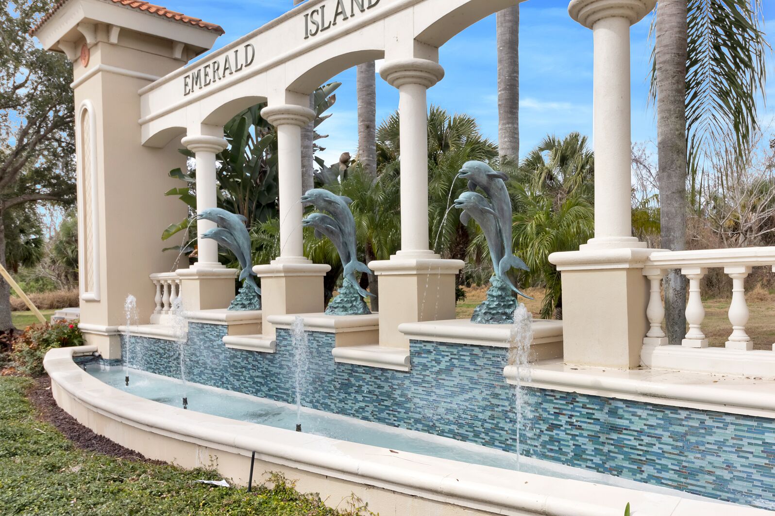 A water feature with dolphin sculptures and the text "Emerald Island" on a building.