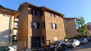 A multi-story building with a beige facade, multiple windows, and a gated entrance. - APPARTAMENTO A 900 METRI DAL LAGO MAGGIORE (Arona)