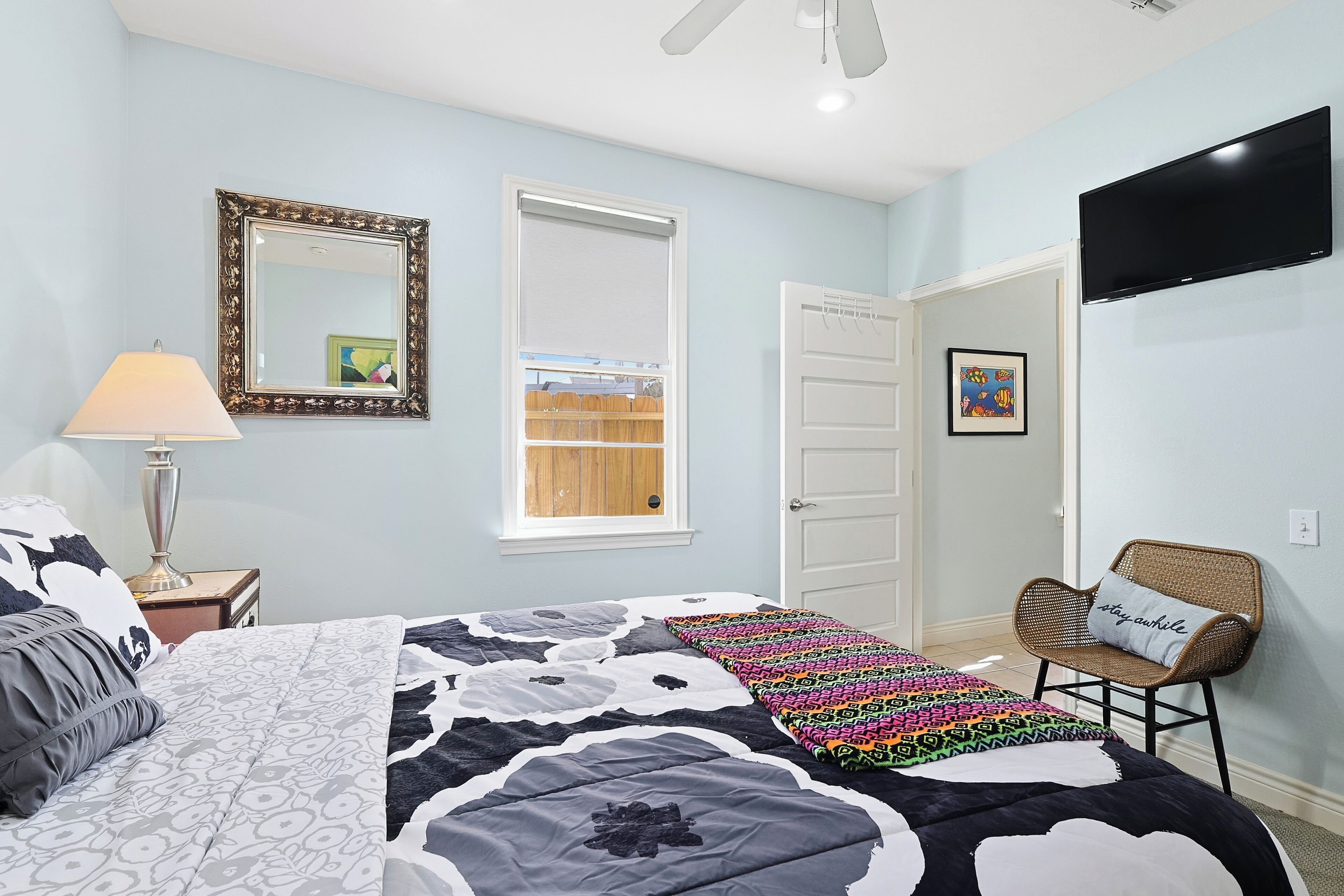 A bedroom with a bed, a chair, a lamp, a TV, and a wardrobe.