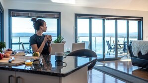 A modern kitchen with a large island, a dining area with a view, and a cozy seating area with a view.