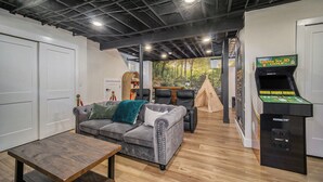 A cozy living room with a grey sofa, a wooden coffee table, and a tent-like structure.