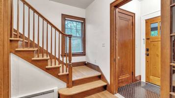 A wooden staircase with a handrail, a window with blinds, and a door with a glass panel.