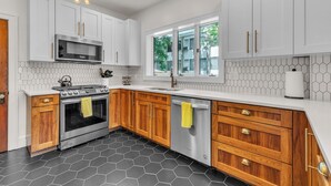 A modern kitchen with white cabinets, a stainless steel stove, and a black tiled floor.