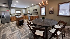A modern kitchen with a central island, wooden cabinets, and a dining area with a round table and chairs.