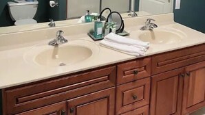 Une salle de bain avec deux lavabos, un grand miroir et un meuble de rangement.