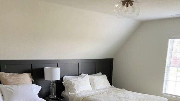 Une chambre d’hôtel avec deux lits, une table de chevet, une lampe et un ventilateur de plafond.