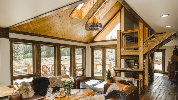 Un vaste espace de vie doté d’un haut plafond, de grandes fenêtres et d’un escalier en bois.