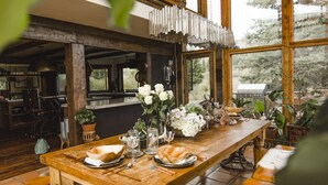 Une table de salle à manger en bois, mise avec des assiettes, des verres et un vase de fleurs.