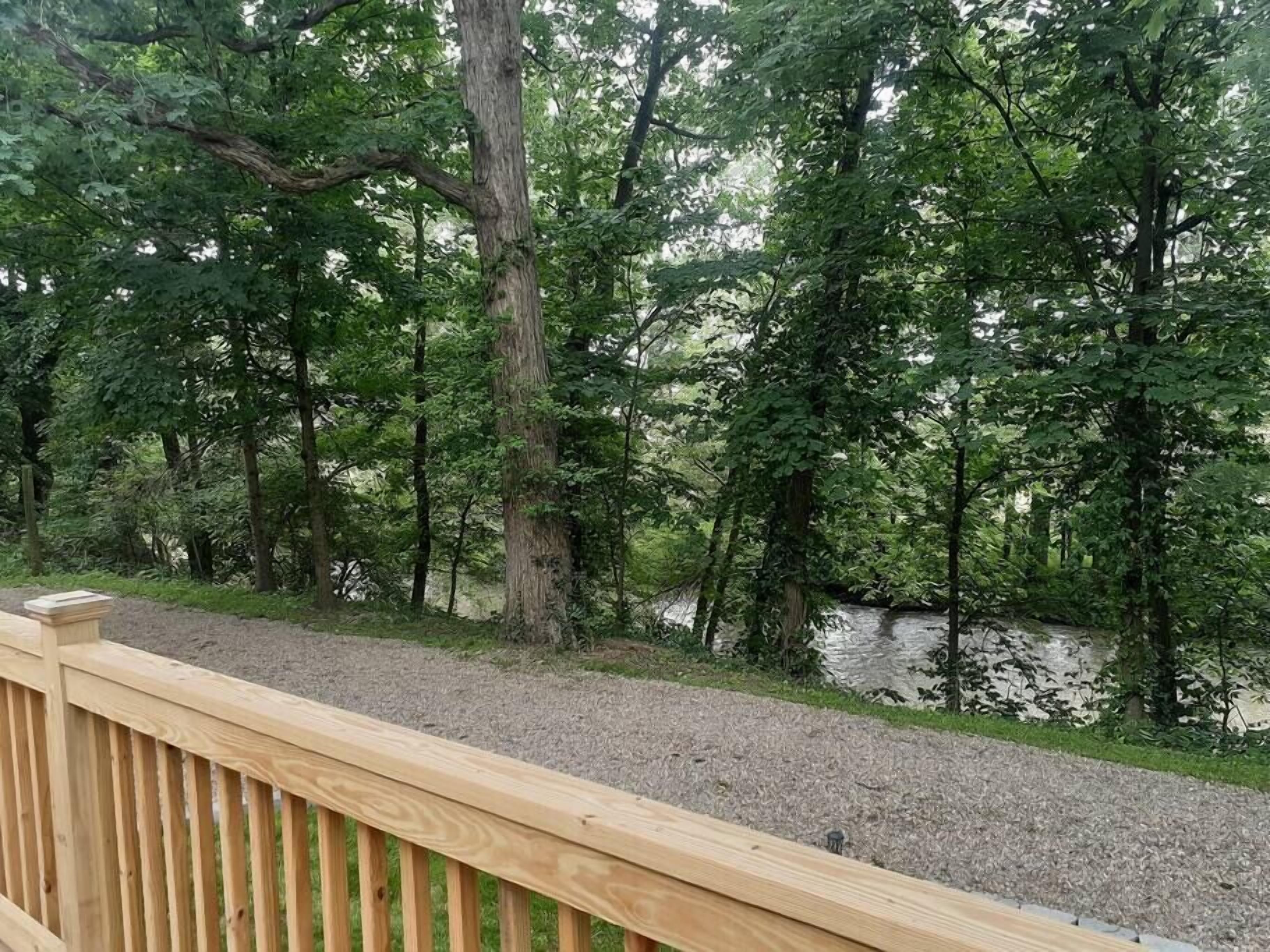 A wooden deck overlooking a river with dense trees in the background.