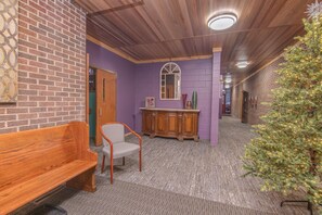 A hallway with a wooden bench, a chair, a cabinet, and a Christmas tree. - Gathering families, friends, & coworkers (Clear Lake)