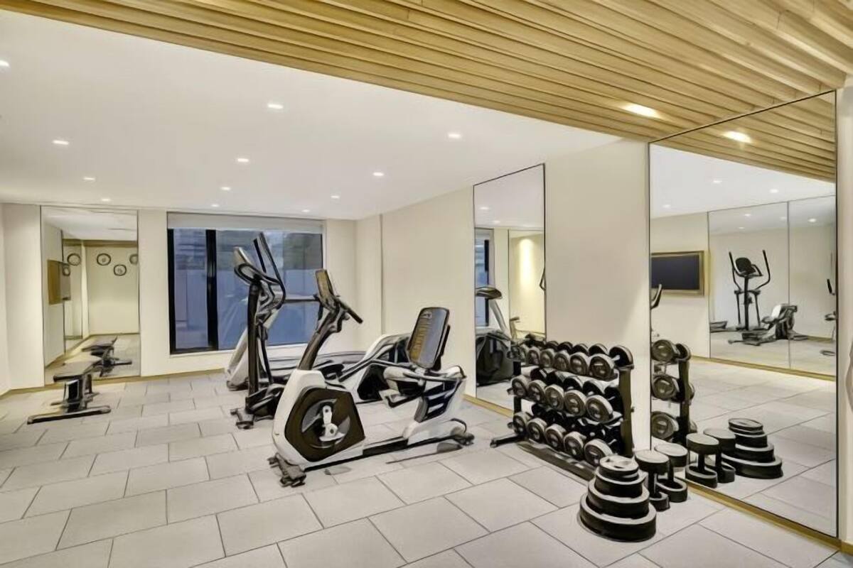 A modern gym with cardio equipment, weightlifting stations, and large mirrors.