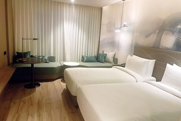 A hotel room with two beds, a sofa, a small table, and a lamp. - Park Inn by Radisson Surat (Surat)