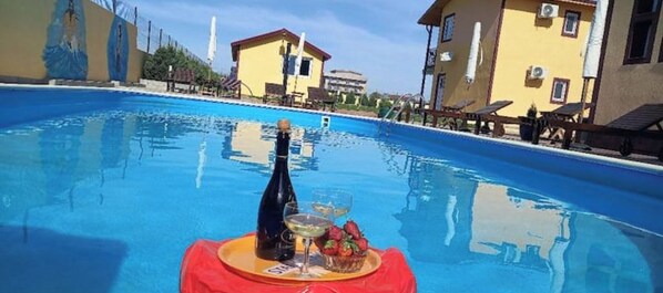 A swimming pool with a table set for a drink and fruit, surrounded by buildings.