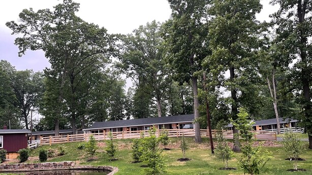 A rustic lodge with multiple cabins, a pond, and a wooden fence. - New Hope Lodge (New Hope)