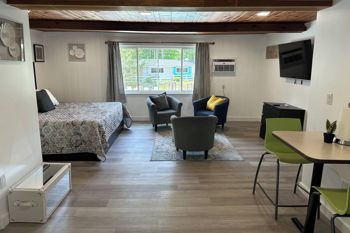A bedroom with a bed, a desk, a chair, and a TV.