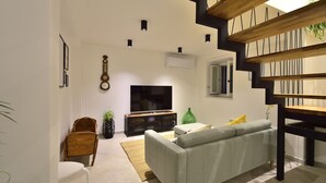 A modern living room with a grey sofa, wooden coffee table, and a flat-screen TV.