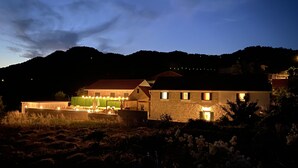 A stone building with a red roof, surrounded by a landscaped area with a pool and outdoor seating.