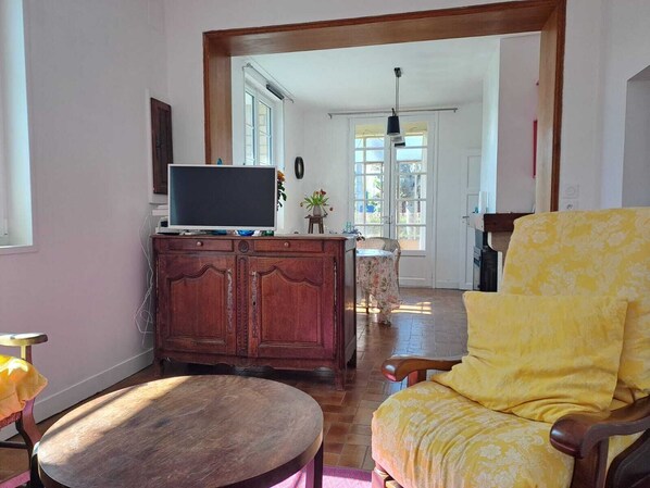 A living room with a wooden cabinet, a television, a yellow armchair, and a small table.
